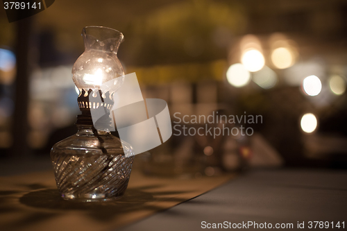 Image of Antique oil lamp with dim light on table in cafe