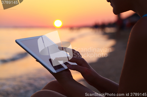 Image of Woman using pad outdoor at sunset