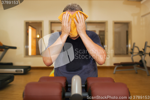 Image of Man wiping face with a towel after training