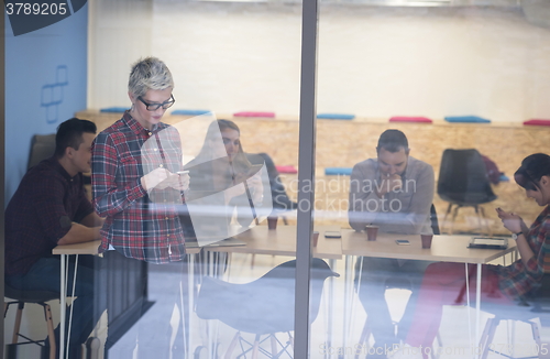 Image of business woman at office speaking by phone  team on meeting in b