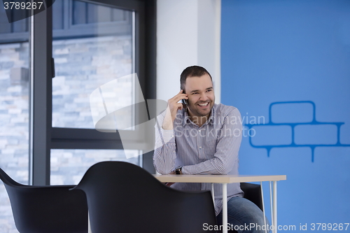 Image of business man talking by phone in office