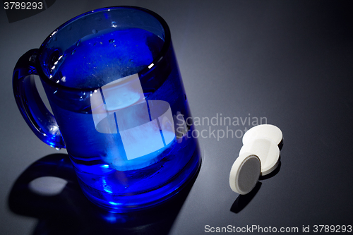 Image of Tablet dissolving in a blue glass of water.