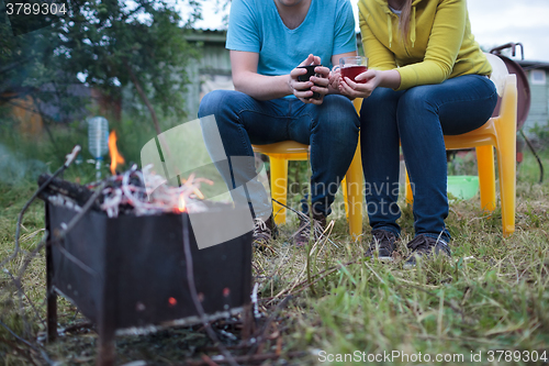 Image of Couple with tea cups in hands near the smouldering fire