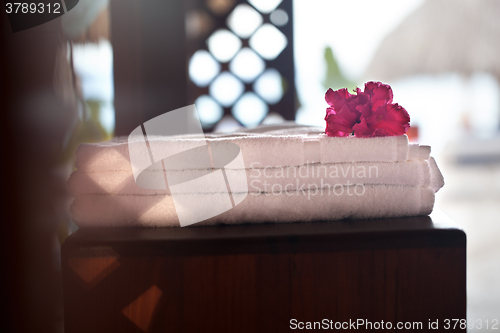 Image of Pile of three white clean towels with flower on top