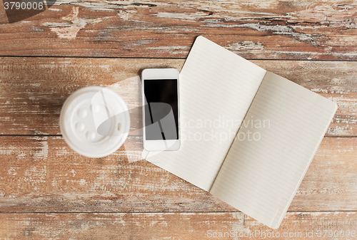 Image of close up of notebook, coffee cup and smartphone