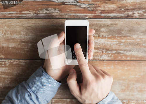 Image of close up of male hands with smartphone on table