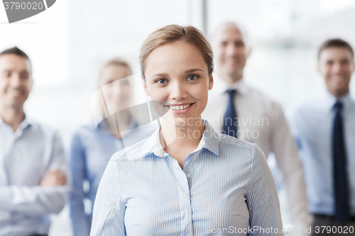 Image of smiling businesswoman with colleagues in office