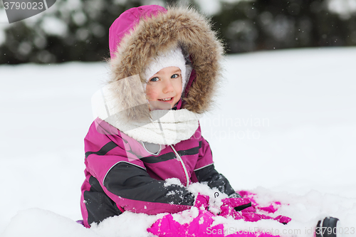 Image of happy kid in winter clothes playing with snow