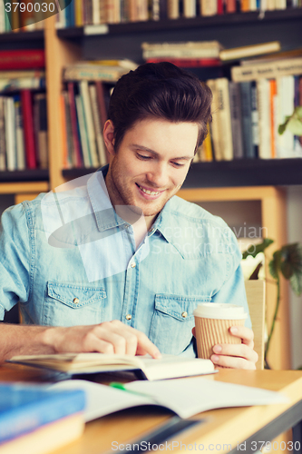 Image of happy student reading book and drinking coffee