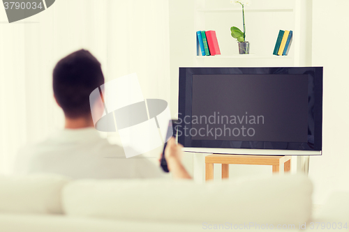 Image of man watching tv and changing channels at home