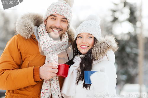 Image of happy couple with tea cups over winter landscape