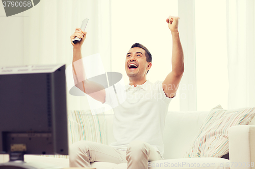 Image of smiling man watching sports at home