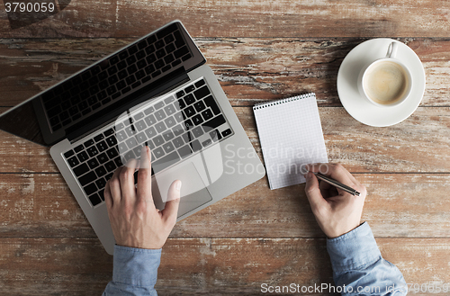 Image of close up of male hands with laptop and notebook