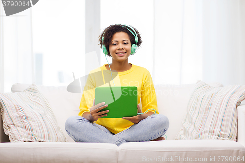 Image of happy african woman with tablet pc and headphones