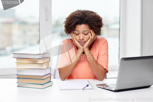 Image of bored african american woman doing homework home