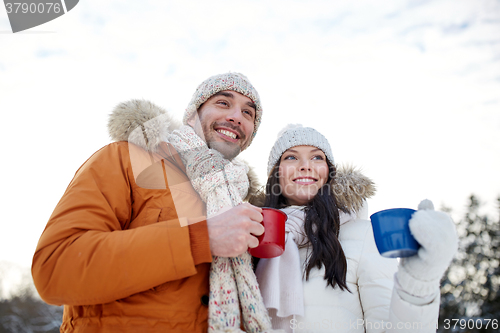 Image of happy couple with tea cups over winter landscape