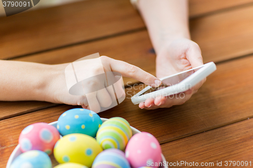 Image of close up of hands with easter eggs and smartphone