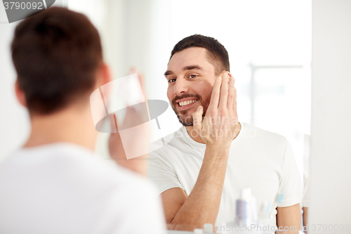 Image of happy man applying shaving foam at bathroom mirror