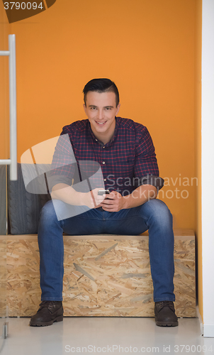 Image of man in crative box working on smart phone