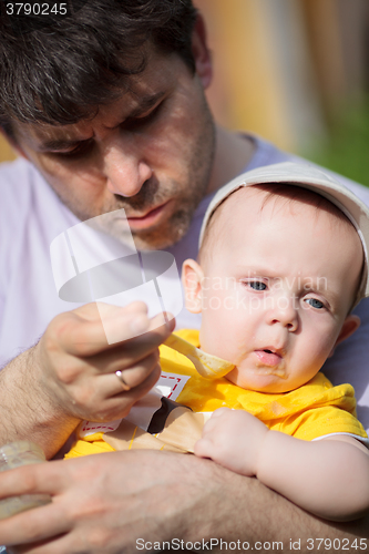 Image of Father trying to feed infant