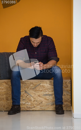 Image of man in crative box working on smart phone