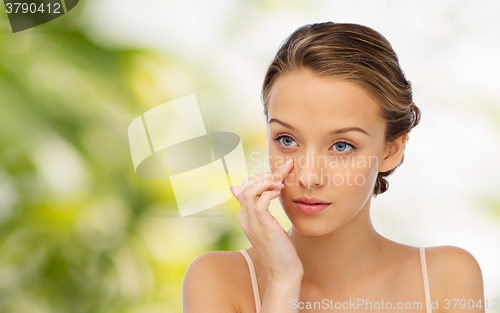 Image of young woman applying cream to her face