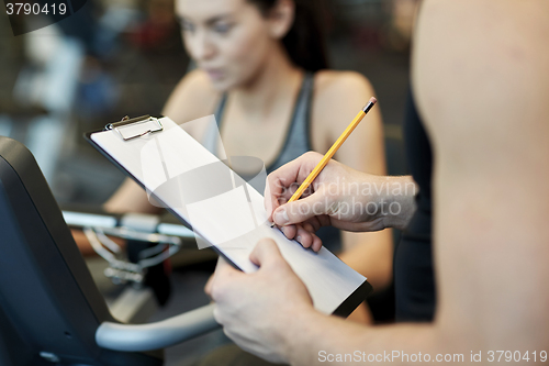 Image of close up of trainer hands with clipboard in gym