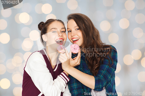 Image of happy pretty teenage girls eating donuts