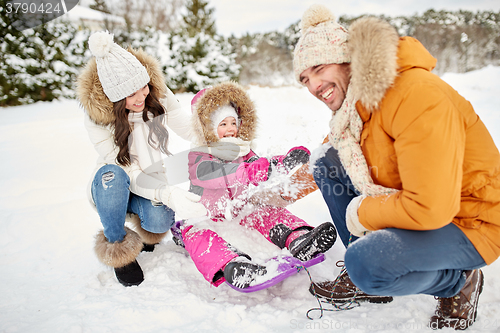Image of happy family with kid on sled having fun outdoors