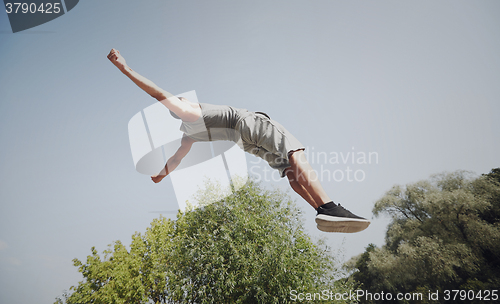 Image of sporty young man jumping in summer park