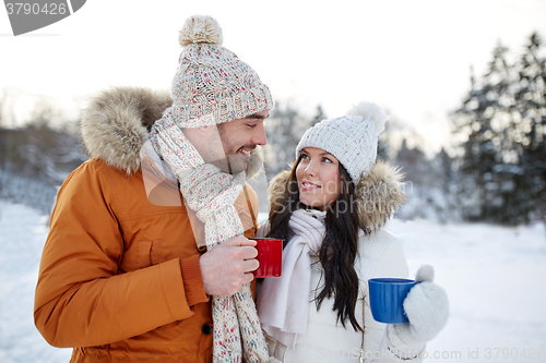 Image of happy couple with tea cups over winter landscape