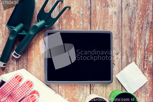 Image of close up of tablet pc and garden tools on table