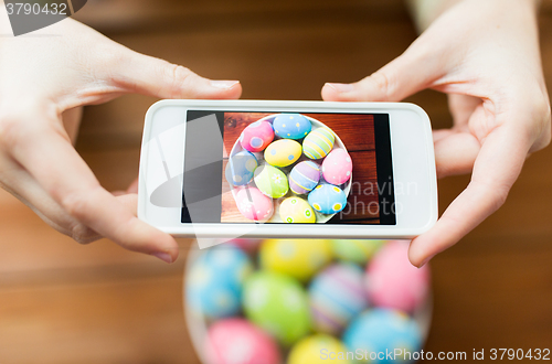 Image of close up of hands with easter eggs and smartphone