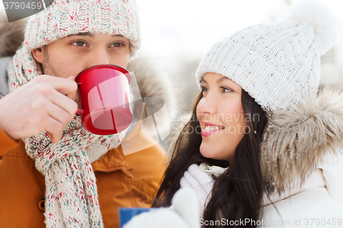 Image of happy couple with tea cups over winter landscape