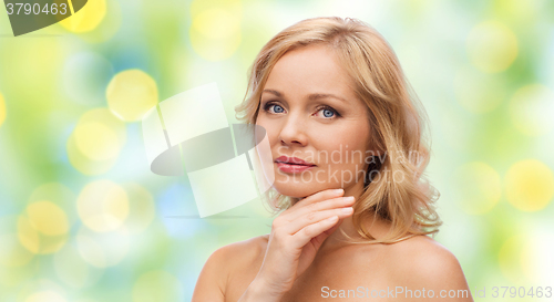 Image of woman with bare shoulders touching face