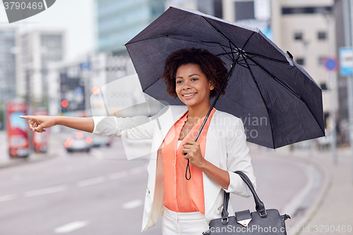 Image of happy african woman with umbrella catching taxi