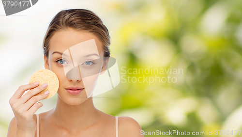 Image of young woman cleaning face with exfoliating sponge