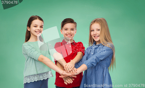 Image of happy children with hands on top over green board