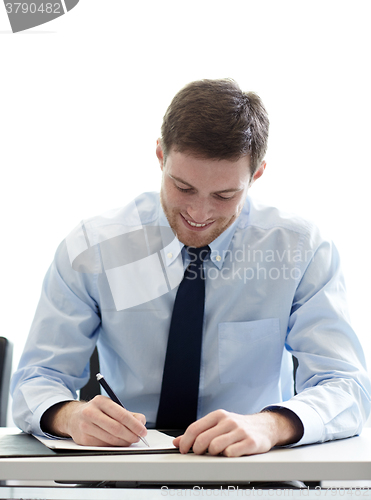 Image of smiling businessman signing papers in office