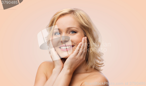 Image of smiling woman with bare shoulders touching face