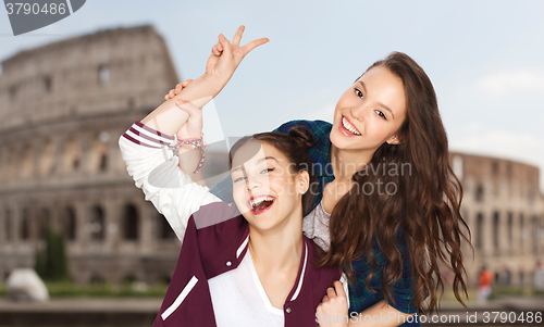 Image of happy teenage girls showing peace over coliseum