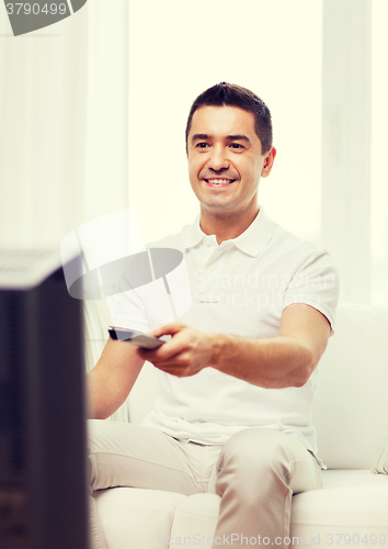 Image of smiling man with remote control watching tv