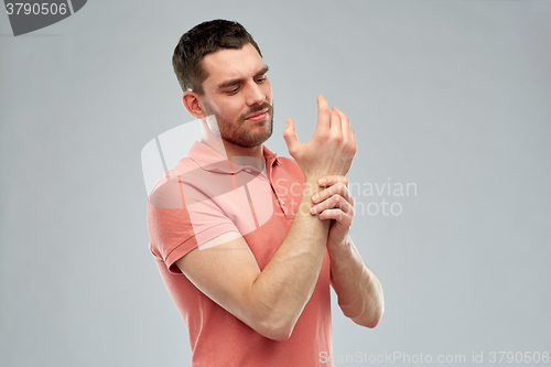 Image of unhappy man suffering from pain in hand