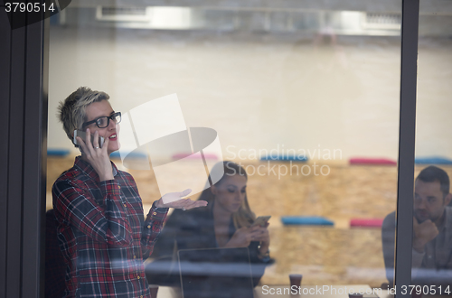 Image of business woman at office speaking by phone  team on meeting in b