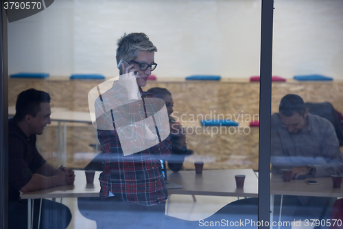 Image of business woman at office speaking by phone  team on meeting in b