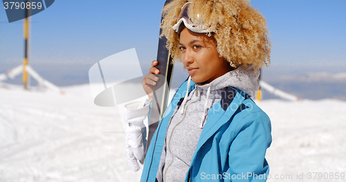 Image of Thoughtful young woman standing holding her skis