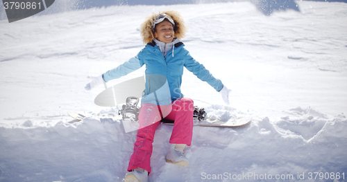 Image of Beautiful young snowboarder sitting on snow