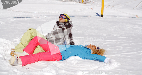 Image of Couple resting on hill after skiing