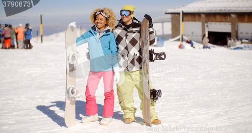 Image of Happy young couple posing with their snowboards