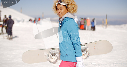 Image of Trendy young woman carrying her snowboard